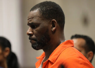 R. Kelly Reportedly Overdoses In Prison As Lawyers Claim Murder Plot, Solitary Abuse R. Kelly in prison clothing with a serious expression during court appearance