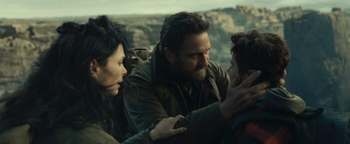 Gerard Butler and Morena Baccarin with their son in Greenland 2 Migration (2026) on HBO Max during an emotional moment in a rugged landscape