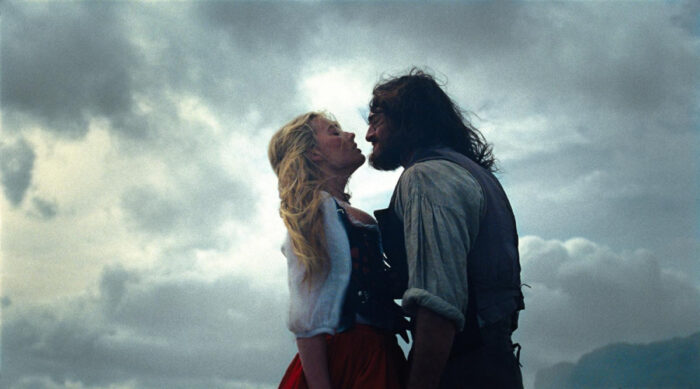 Margot Robbie and Jacob Elordi in Wuthering Heights (2026) on HBO Max, sharing an intimate moment in a dramatic, moody landscape